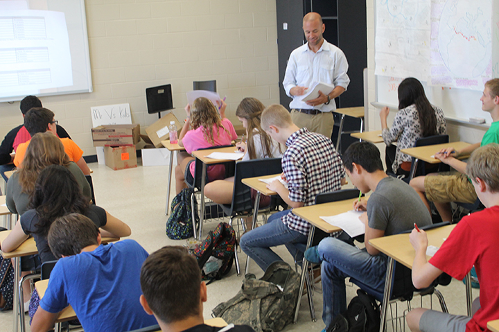 Mr. V hands out the World History exam to students for the end of the year.