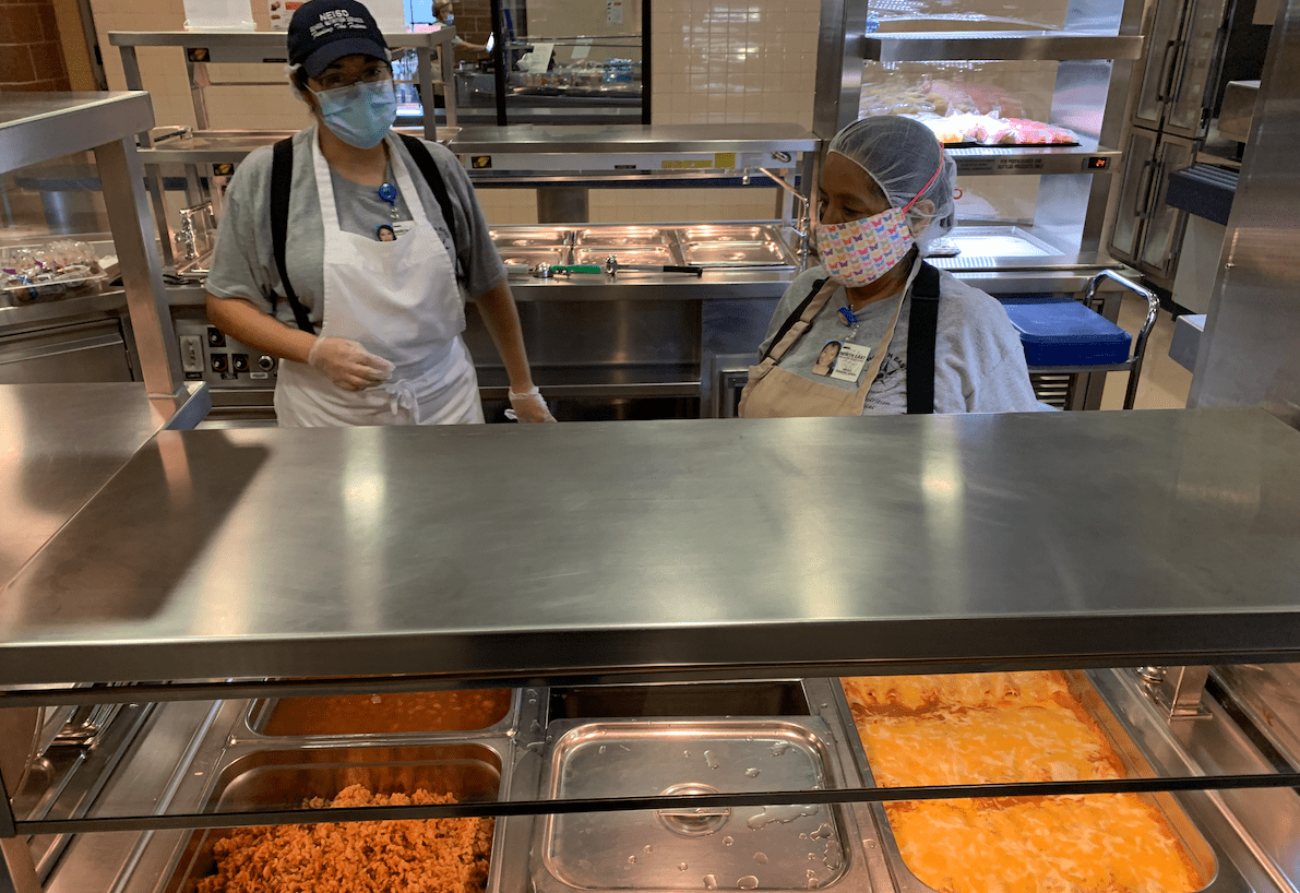 Cafeteria worker prepare enchiladas for student lunches.