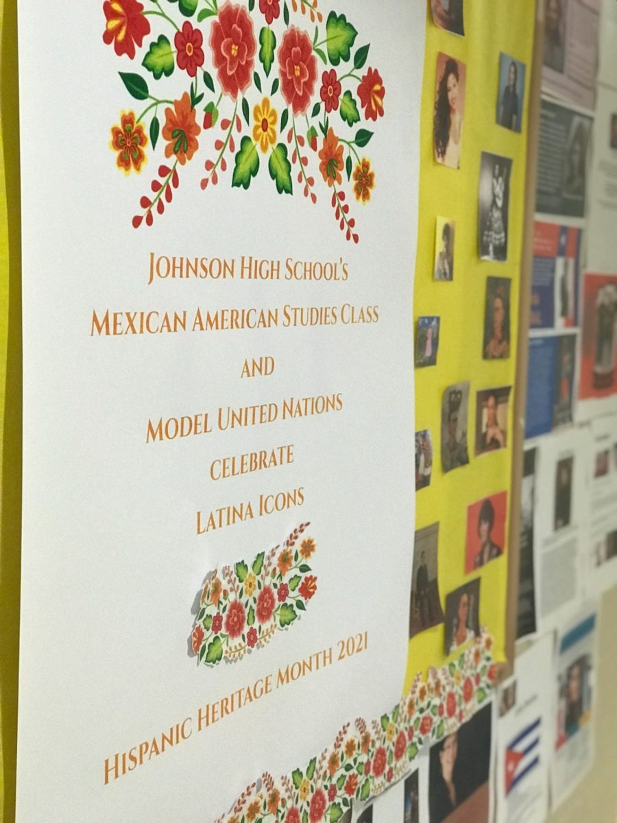 A brightly colored poster board is decorated with red and orange flowers. The poster reads Johnson High Schools Mexican American Studies Class and Model United Nations Celebrate Latina Icons, Hispanic Heritage Month 2021. The poster is surrounded by bright photos of various Latina Icons in Mexican American history.