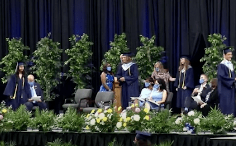Johnson students walking the stage in their navy caps and gowns for graduation.