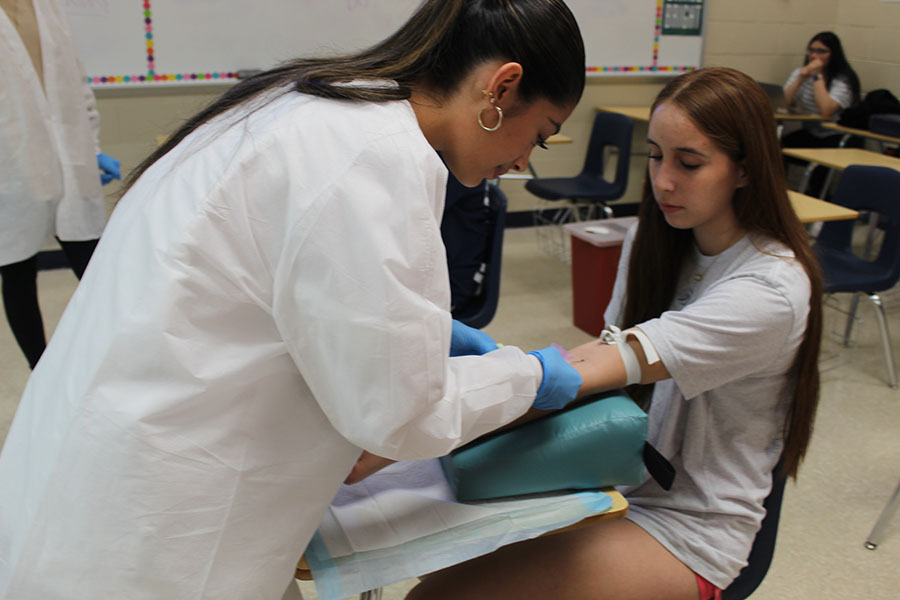 OUT FOR BLOOD
After hearing about an opportunity to get service hours, junior Ava Castillo gets her blood drawn by junior Tatiana Solis. Solis is learning to draw blood for her Principles of Health Science class. “I did not feel nervous at all, the whole process was easy and did not hurt,” Castillo said. photo by Addison Brown
