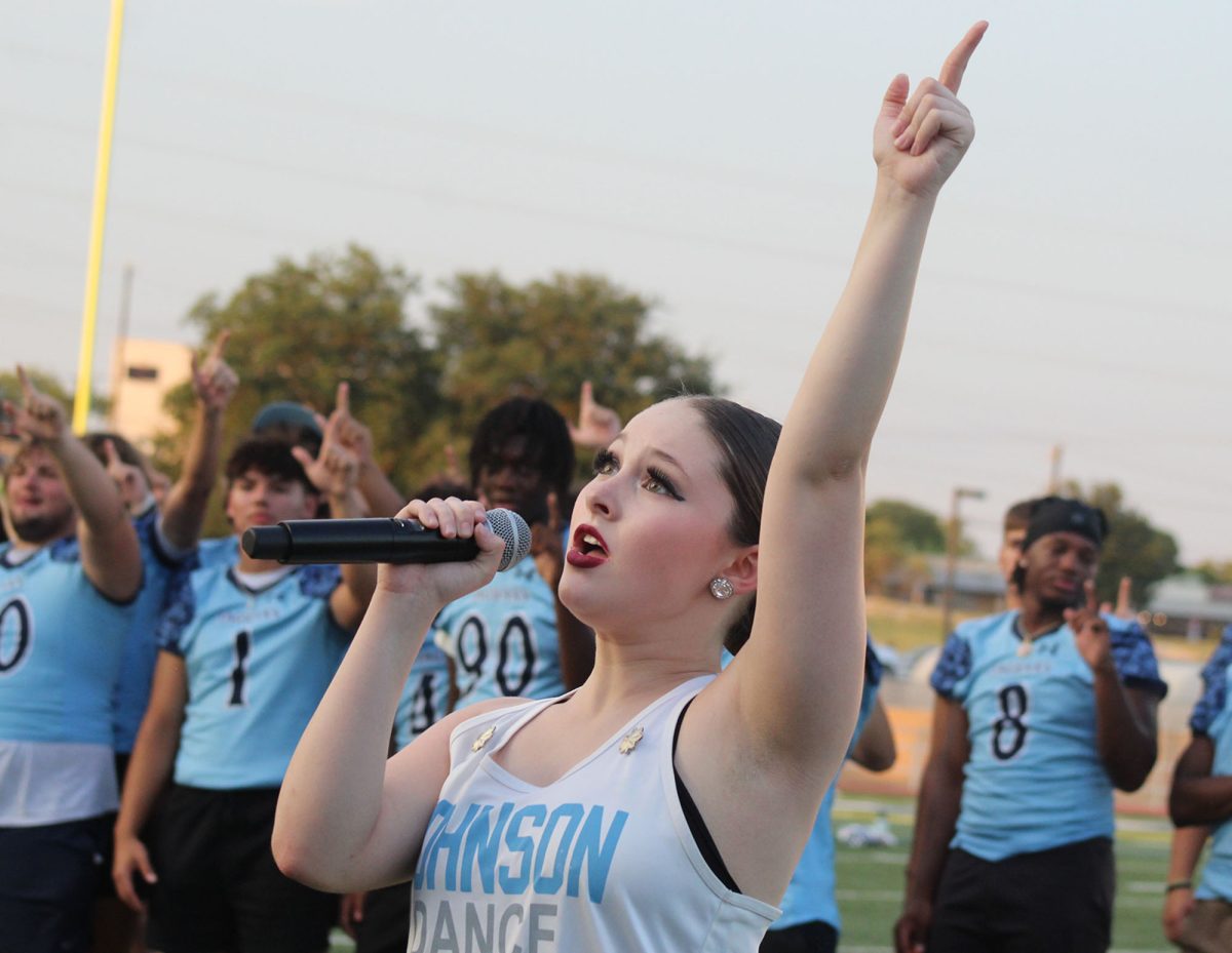 Junior Peyton Shore sings the Johnson alma mater while holding her 'J' up at Meet the Jags. This is Shore's first time singing the alma mater for the school, after she was asked by Mrs. Brown. "It's a big honor for me," Shore said. "I've always loved to sing and I love being on a big stage - or in this case a field - in front of a bunch of people. I was born a performer and I love all kinds of fine arts," Shore said.